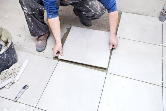 Tiling Floor & Wall. The tiler builder arranges the bathroom ceramics.  Laying tiles on the floor