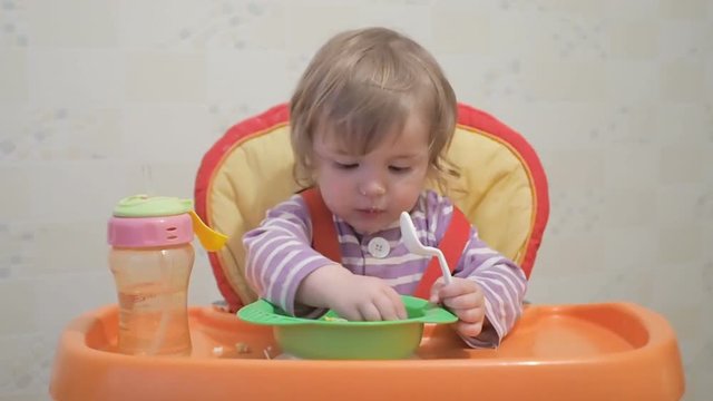 Dirty Little baby boy eats porridge with his hands. Son sitting in the chair,  highchair.