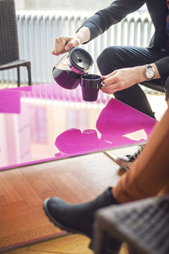 Low section of businessman pouring coffee in mug at creative office