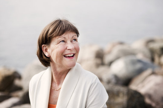 Mature woman laughing while looking up against rocks