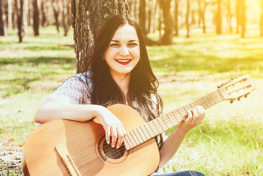 woman playing an acoustic guitar outdoor