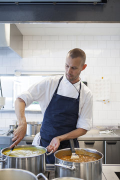 Male chef stirring gravy in utensil at commercial kitchen