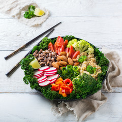 Healthy vegan buddha bowl with kale leaves and raw vegetables