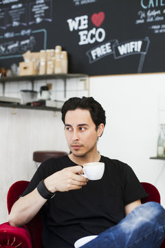 Thoughtful man looking away while holding coffee cup at cafe