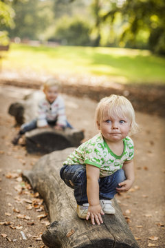 Baby boy crouching on log at park