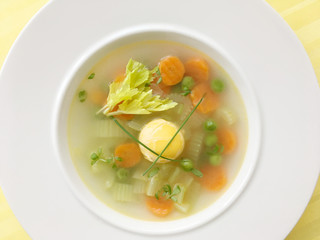 Vegetable soup with carrot, celery, peas and egg. Decorated by cress and chives herbs. Top view.