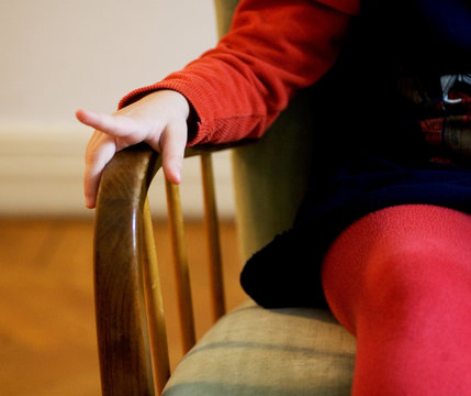 Midsection of girl sitting on chair at home