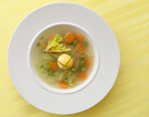 Vegetable spring soup with carrot, peas, celery and egg. Top view.