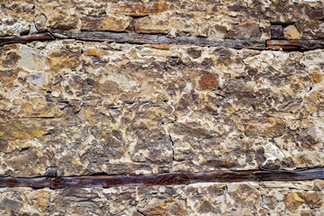Wall of old stone with wooden inserts
