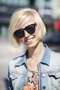 Happy young woman wearing sunglasses in city on sunny day