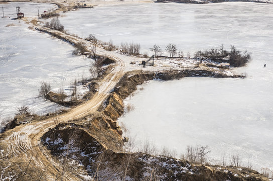Isthmus in frozen water in a sandy quarry in the winter. Winter landscape. Road in a frozen sand quarry