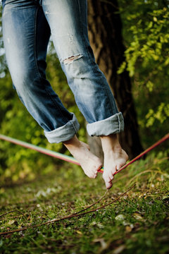 Tilt shot of man balancing on tightrope over grass at park