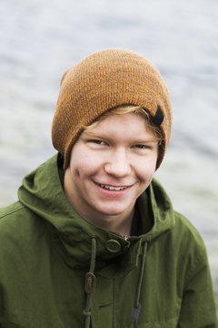 Portrait of happy teenage boy against lake