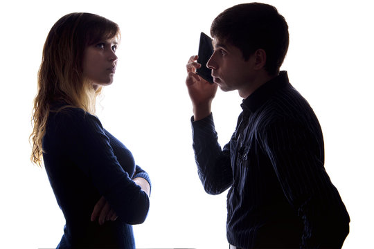 Silhouette of a young woman is jealous and offended because of the fact that a man communicates by phone