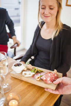 Cropped hand of waiter serving food to woman in restaurant
