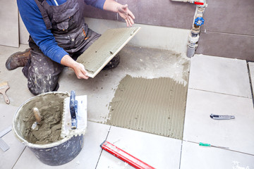 Tiling Floor & Wall. The tiler builder arranges the bathroom ceramics.  Laying tiles on the floor