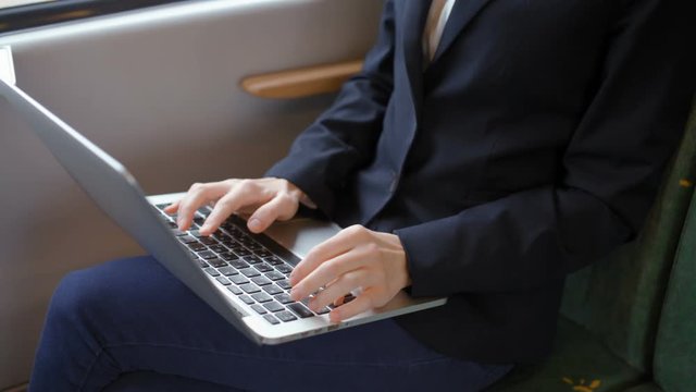 Young Beautiful Business Lady is Typing Text on a Laptop while Going by Train