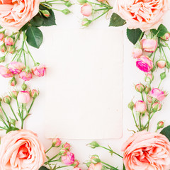 Floral frame with pink roses and paper vintage card for calligraphy on white background. Flat lay, top view. Floral background.