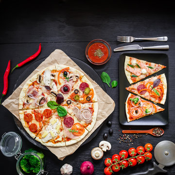 Pizza with ingredients, spices, oil and vegetables on dark background. Flat lay, top view. Tasty food