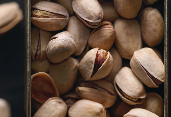 Roasted pistachios on the dark background. Macro food photography. Top view.