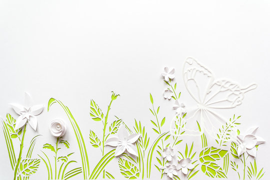 Summer flowering meadow. White flowers carved from paper on a white background with green leaves © EkaterinaVladimirova