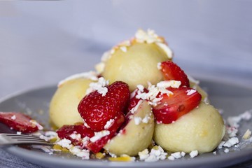 Traditional czech dish. Quark dough dumplings with fruit filling, These are with strawberries. Topped with grated quark,powdered sugar,sliced strawberries and melted butter.