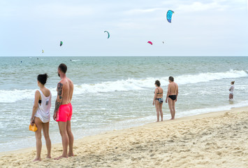 Mui Ne, Vietnam - February 19th, 2017: Travelers are watching Kite Surfers on a beautiful summer afternoon in Mui Ne, Vietnam.