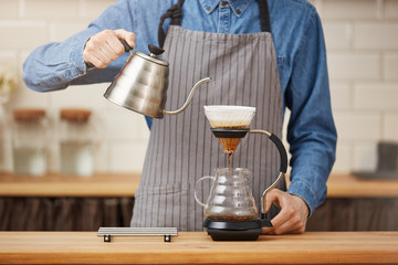 Coffee brewing gadgets. Male bartender brewing pourover coffee at bar.