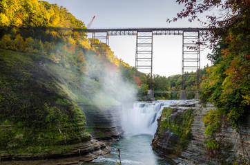 Plakat Railroad Bridge over a Gorge under Clear Sky at Sunset. At the Foot of the Gorge there is a Beautiful Waterfall