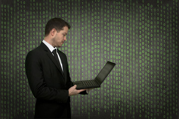 Mann in Anzug und Krawatte hält Notebook - im Hintergrund sind Nullen und Einsen