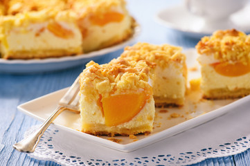 Cheesecake with peaches on blue wooden background.