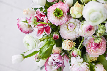  Flower arrangement with tulips and ranunculus on a white wooden floor. Spring flower 