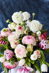  Flower arrangement with tulips and ranunculus on a white wooden floor. Spring flower 