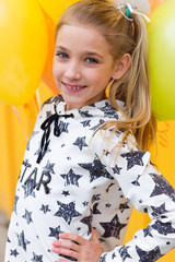 Portrait of a beautiful blonde girl with gel colored balls on a yellow background