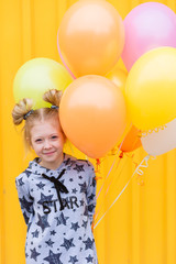Fototapeta na wymiar Portrait of a beautiful blonde girl with gel colored balls on a yellow background