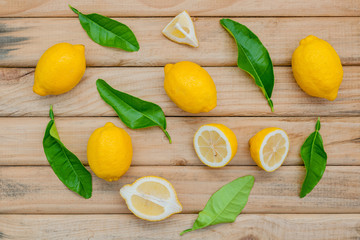 Fresh lemon and lemon leaves on rustic wooden background. Lemon and lemon slice on wooden table with flat lay.  Fresh citrus fruit background.