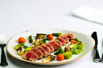 Salad of tuna and vegetables with a white tablecloth, studio light
