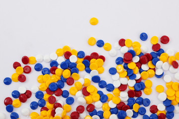 Colorful plastic polymer granules on white background.