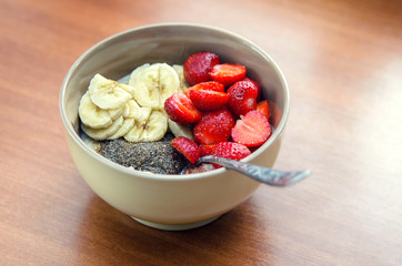 Summer breakfast/ Oatmeal porridge with slices of strawberries, bananas, bran and butter