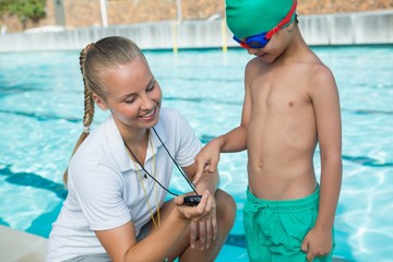 Female trainer showing stopwatch to boy