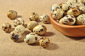 Fototapeta premium Quail eggs in a wooden bowl in a sacking