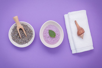 Fototapeta na wymiar Homemade skin care lavender bath salt beauty treatment, towel and lavender flower on purple background flat lay.