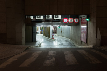 Entrance to underground car park at night. Outdoor area is dark, carpark is lit by artificial light.