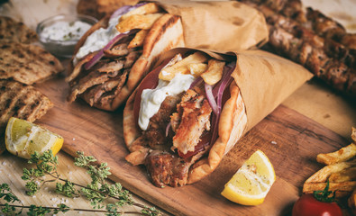 Greek gyros wrapped in pita breads on a wooden table - obrazy, fototapety, plakaty