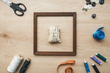 Scissors, threads, needles, tapes, buttons, pins, cloth on the wooden background. Sewing tools.
