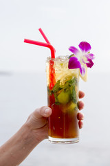 Refreshing drink with lime, mint and pineapple on a tropical beach, close up. Mojito cocktail