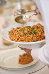 Dettaglio di un cameriere che versa un piatto di fregola in un piatto