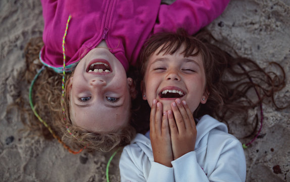 young friends laughing while lying on the beach