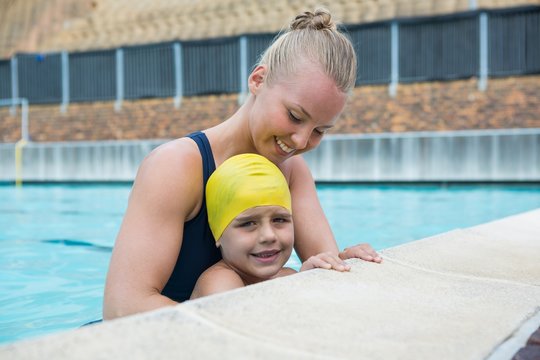 Female instructor and young boy relaxing at poolside