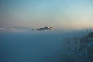 Top of Caldera cliff above the fog at sunny sunrise, village of Imerovigli, Santorini island, Greece